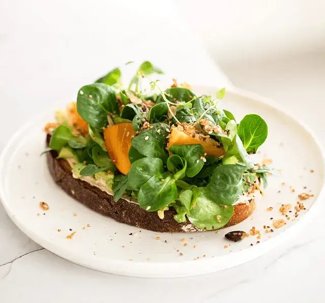 An open sandwich topped with fresh salad
